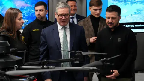 PA Media Prime Minister Sir Keir Starmer (centre) and Ukrainian President Volodymyr Zelensky ( right) attend a presentation of Ukrainian military drones at an undisclosed location, during his visit to Ukraine to sign a new long-term partnership deal with Volodymyr Zelensky