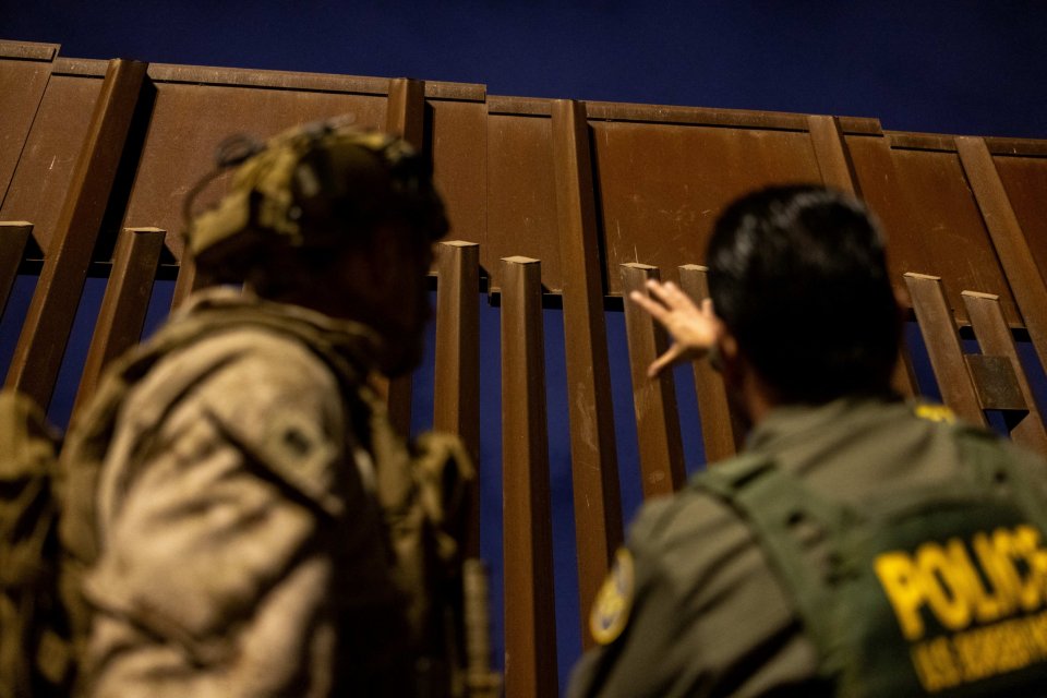 Two officers at the border wall.