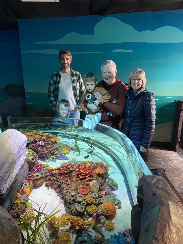 Family posing in front of a large aquarium.