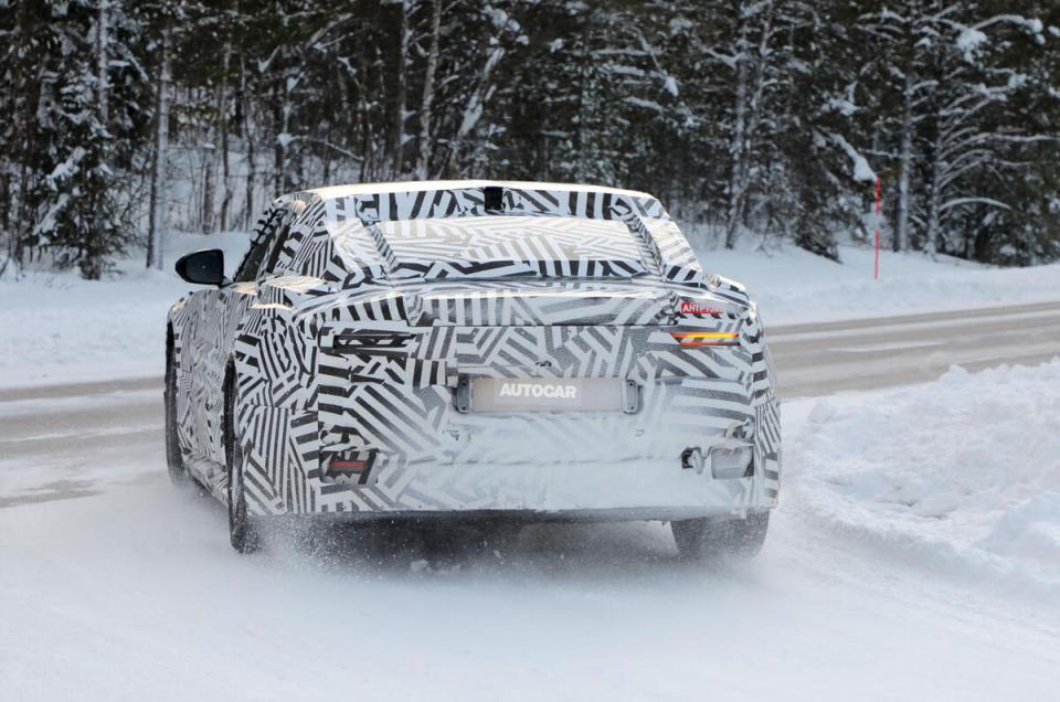 Rear view of a camouflaged electric vehicle driving in the snow.