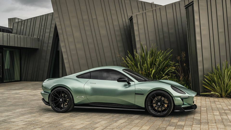 A light green sports car parked in front of a modern building.