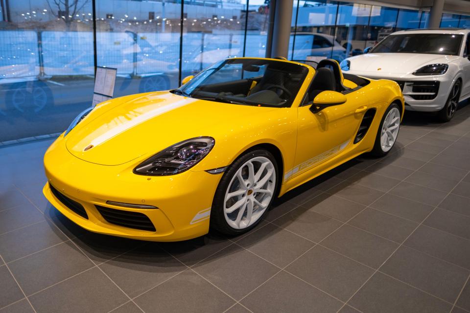 Yellow Porsche Boxster Spyder RS convertible in showroom.