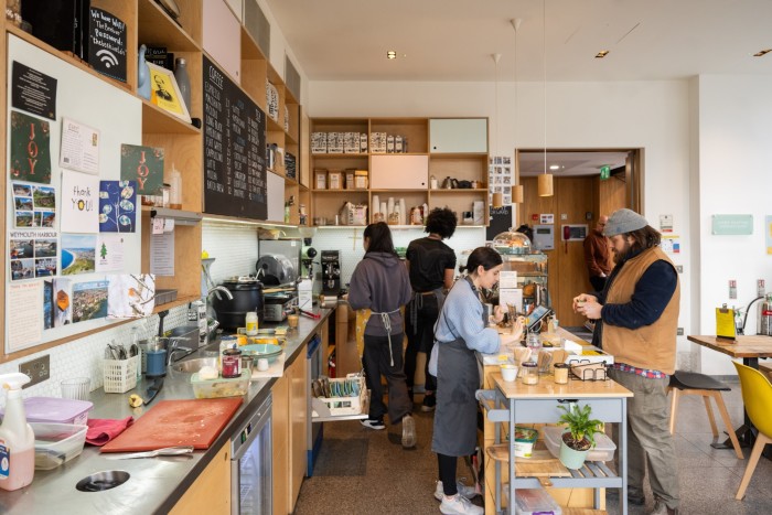 A bustling café with staff working behind the counter, a customer ordering, and a cozy, decorated interior