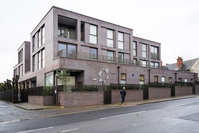 A modern brick building with balconies and a geometric logo on the facade