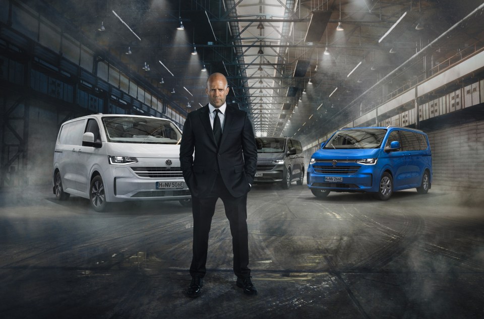 Man in suit standing between two vans in a warehouse.