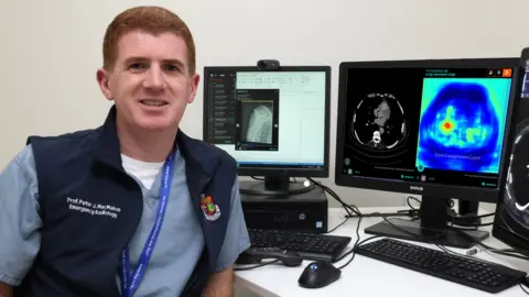 Mater Hospital Prof Peter McMahon, a consultant radiologist at the Mater, sits in front of screens showing medical scans.