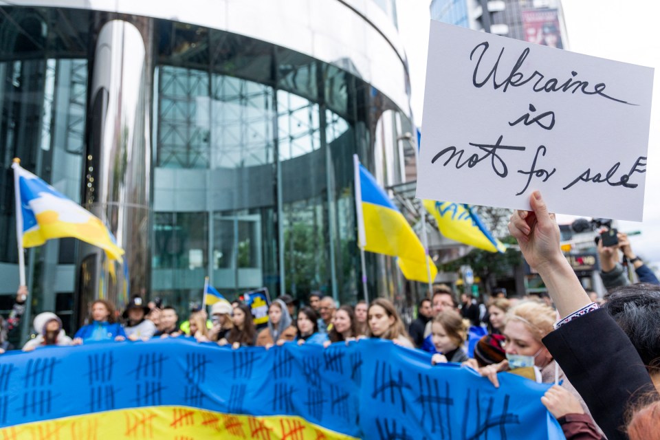 Protestor holding sign reading "Ukraine is not for sale" at a demonstration.