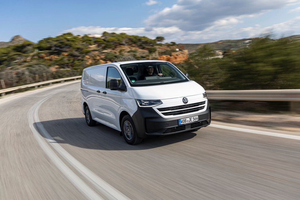 White Volkswagen van driving on a winding road.