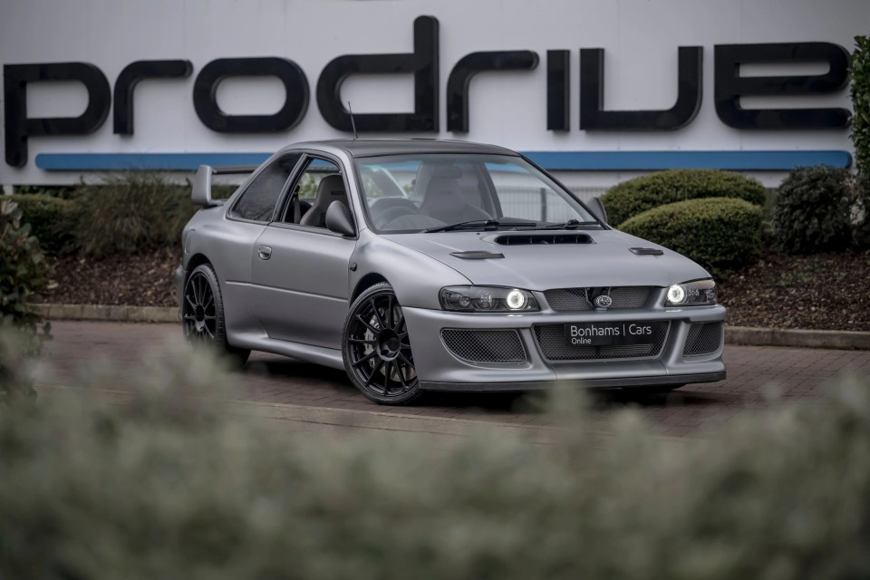 Silver Subaru Prodrive P25 in front of Prodrive building.