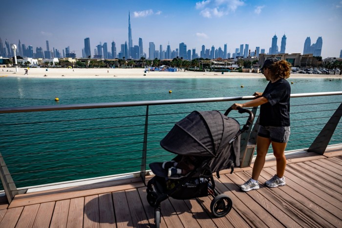 A woman pushes a pram along a walkway near Jumerah beach in Dubai