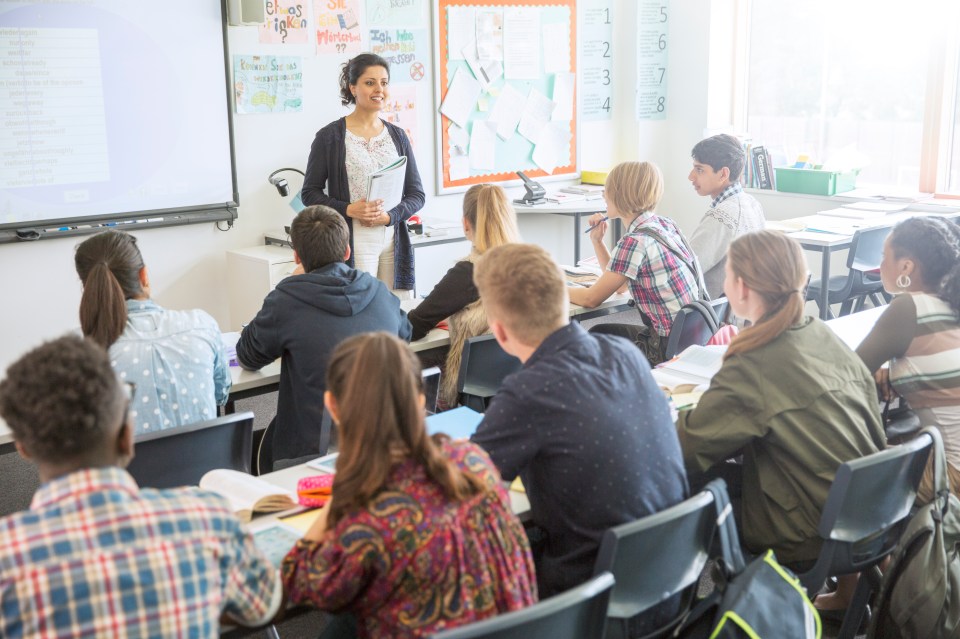 Teacher lecturing high school students in a classroom.