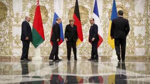 Alexander Lukashenko, Vladimir Putin, Angela Merkel, François Hollande and Petro Poroshenko walk past national flags at the presidential residence in Minsk on February 11 2015