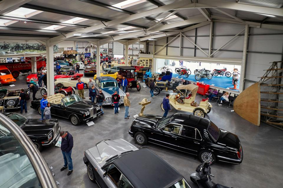 Interior of a motor museum with many classic cars and motorcycles.