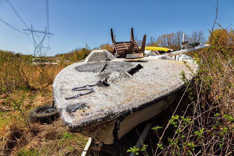 Abandoned boat in overgrown field.