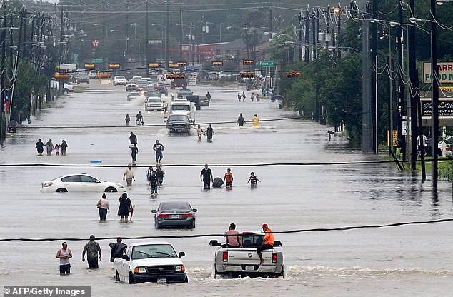 Houston, Texas is the fastest-sinking city in the country, with over 40 percent of its area subsiding more than one fifth of an inch per year. Pictured: people walk through floodwaters in Houston during Hurricane Harvey in 2017